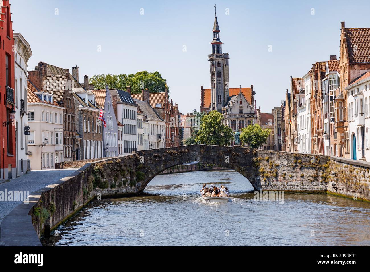 Ponte di pietra sul canale Langerei a Bruges, con una barca turistica che passa sotto il ponte, Brugge, Belgio Foto Stock