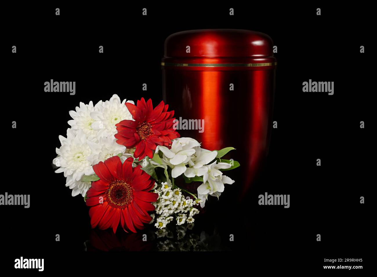 Urna funeraria in lutto accanto a un bouquet di fiori. Isolato su sfondo nero. Foto Stock