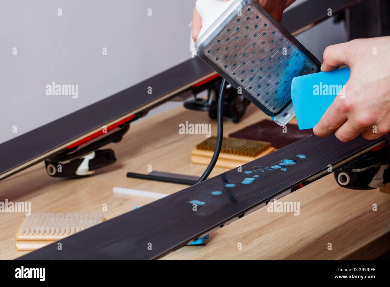 Il lavoratore scioglie la cera per rivestire la base sciistica per una scorrevolezza fluida Foto Stock