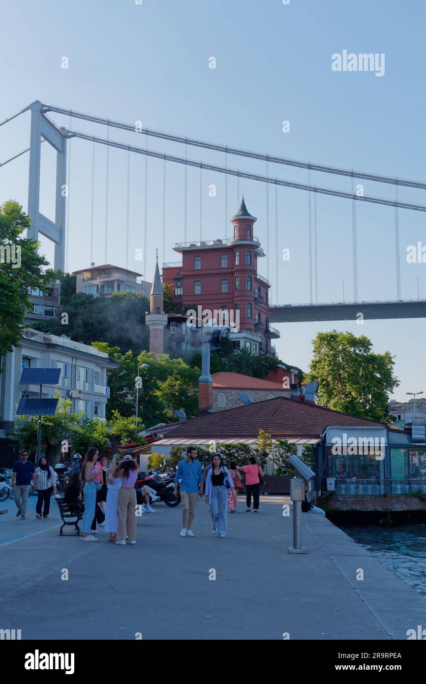 La gente cammina sul lungomare di Rumeli con il Fatih Sultan Mehmet Bridge, noto anche come secondo ponte sul Bosforo, alle spalle, Istanbul, Turchia Foto Stock