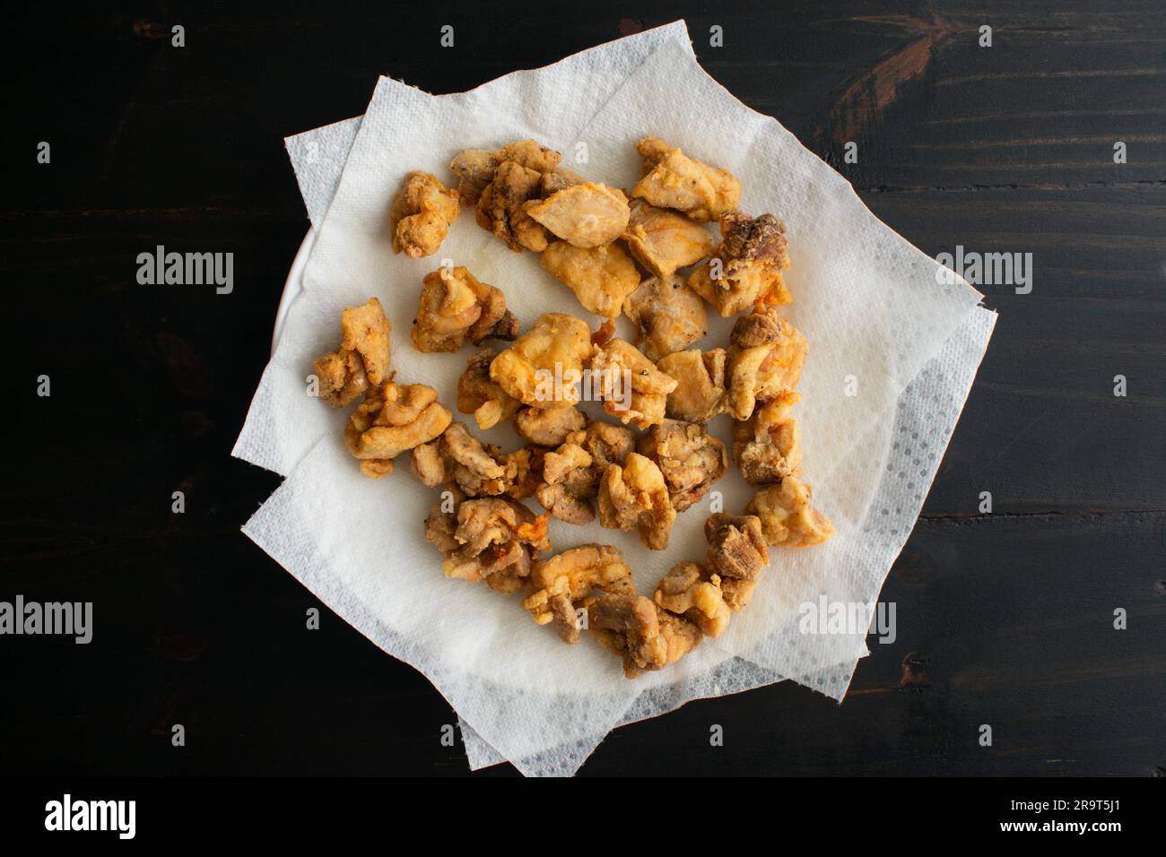 Pezzi fritti di pollo che sgocciolano su asciugamani di carta: Pepite di pollo fritte su un piatto ricoperto di carta Foto Stock