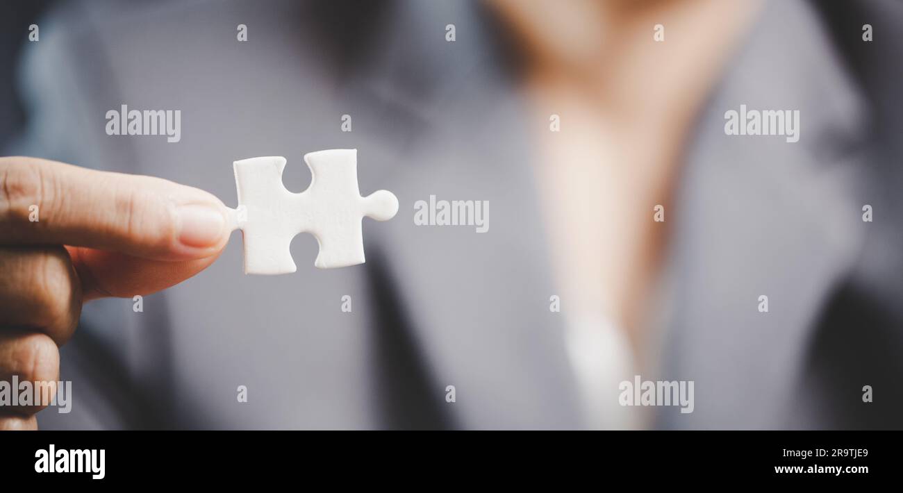 Donna d'affari mano che tiene l'idea del pezzo del puzzle per la strategia e la soluzione. La parte di primo piano di due seghetto bianco si collega tra loro. Concetto di Join coo Foto Stock