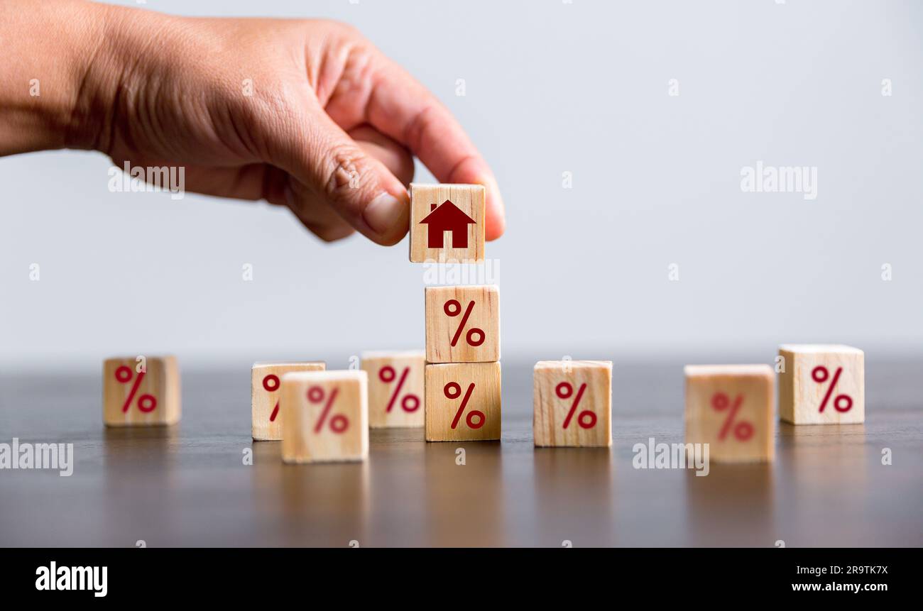Costruire a mano una casa con cubetti di legno con il segno di percentuale su di loro. Nozione di tassi di interesse sui mutui ipotecari finanziari, mutui per la casa, rifinanziamento delle abitazioni, Foto Stock