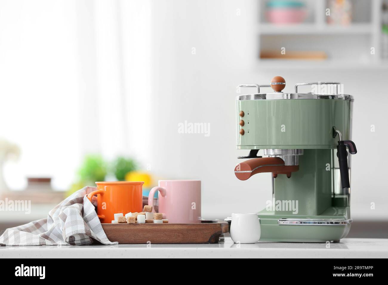 Macchina per il caffè moderna e tazze di espresso caldo sul tavolo in  cucina Foto stock - Alamy
