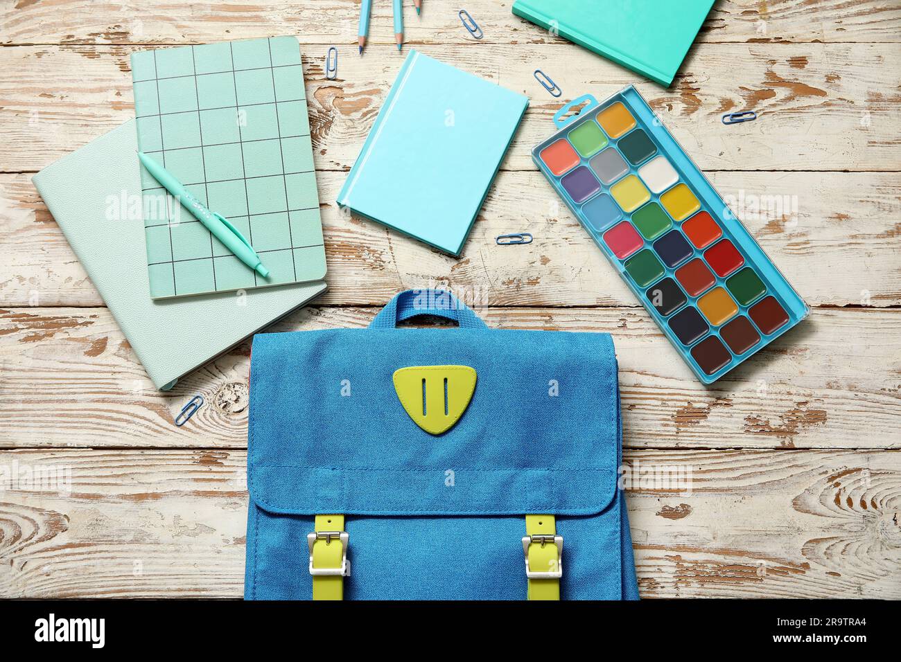 Zaino scuola blu con acquerelli, quaderni e spille di carta su sfondo di  legno Foto stock - Alamy