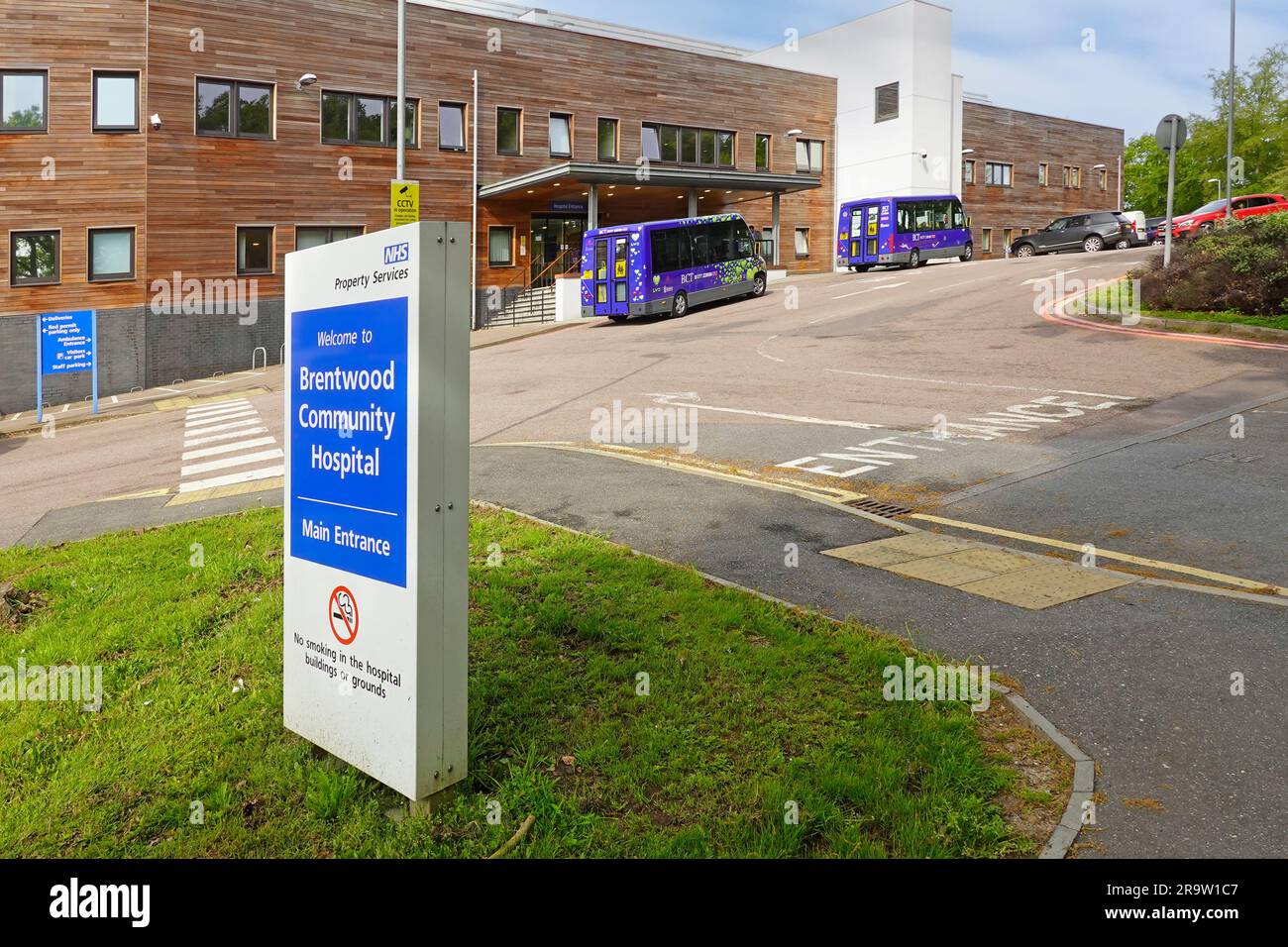 Cartello del NHS Brentwood Community Hospital e edificio per parcheggio auto, uscita di ingresso e ingresso dei pazienti con tettoia alle strutture di accoglienza Essex England UK Foto Stock