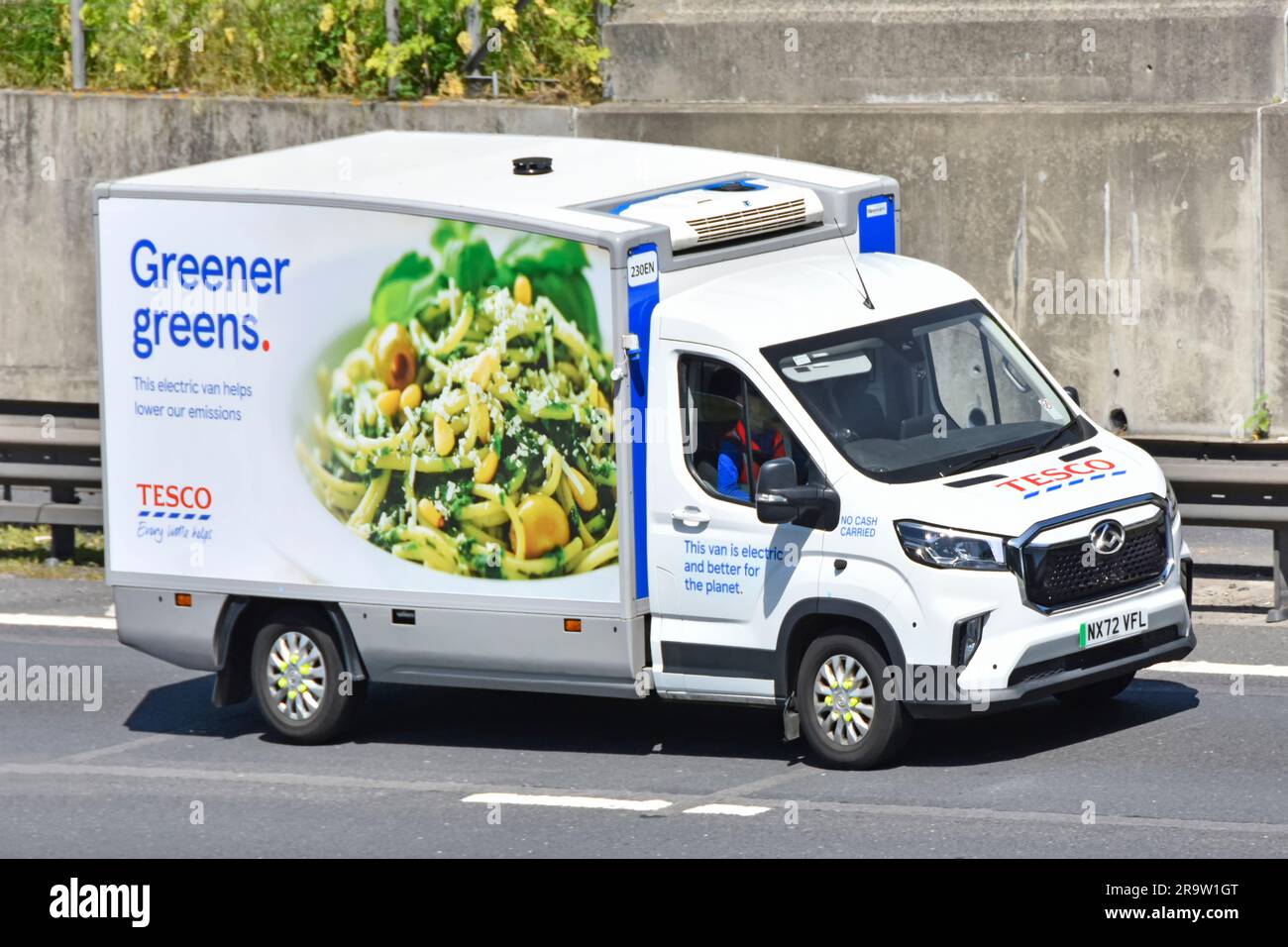 Supermercato Tesco elettrico catena di approvvigionamento alimentare vendita al dettaglio fornitura di furgoni di ordini di acquisto di generi alimentari online che viaggiano lungo la strada autostradale M25 Regno Unito Foto Stock