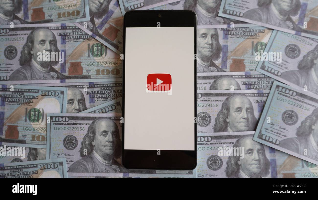 Logo YouTube su smartphone e stack di denaro. Monetizzazione del canale, contenuti video e concetto di profitto Foto Stock