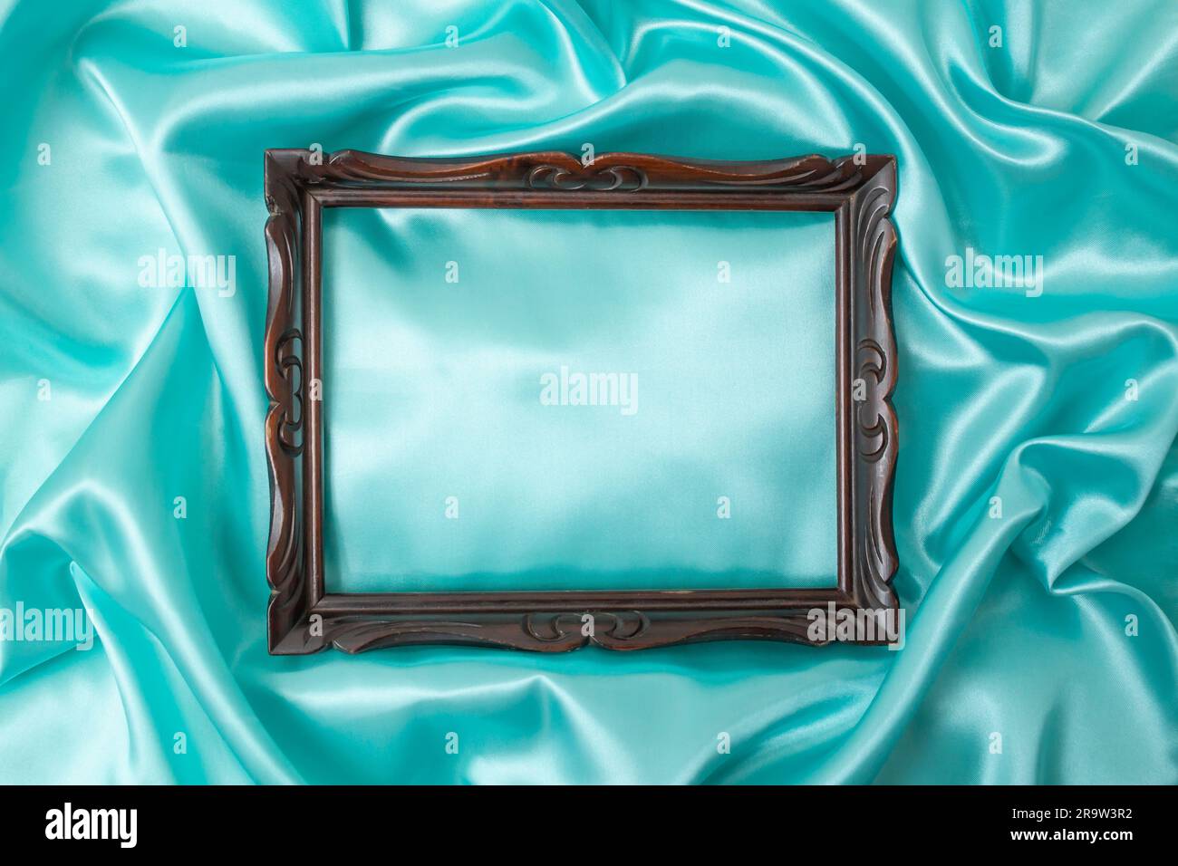 Splendido raso setoso verde blu. Morbide pieghe di tessuto lucido e cornice in legno vintage. Foto Stock