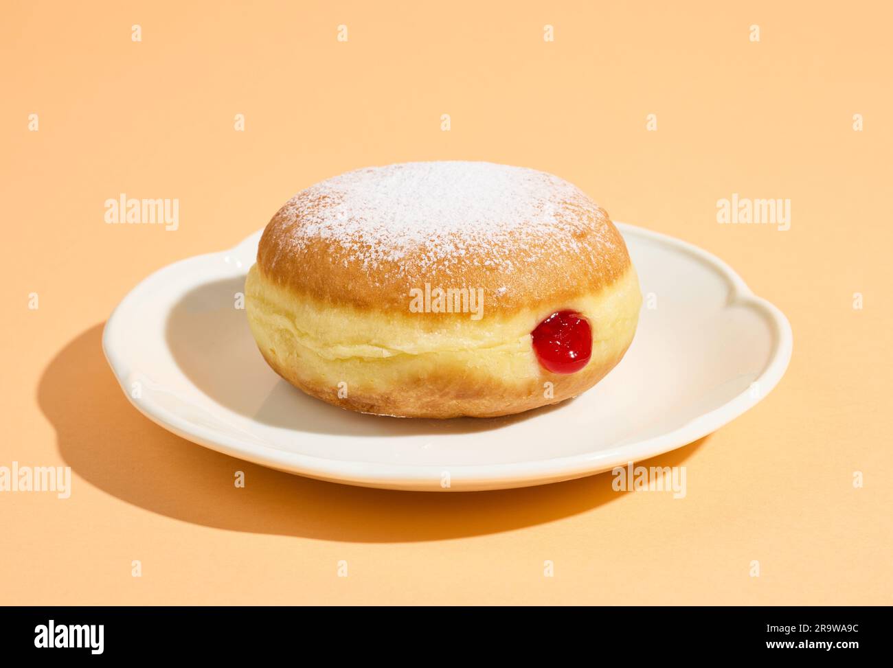 ciambella di gelatina appena sfornata su piastra bianca isolata su fondo arancione Foto Stock