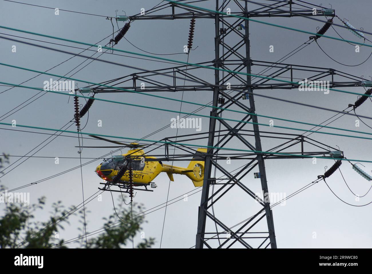 Elicottero Airbus giallo vicino a linee elettriche troppo alte Foto Stock