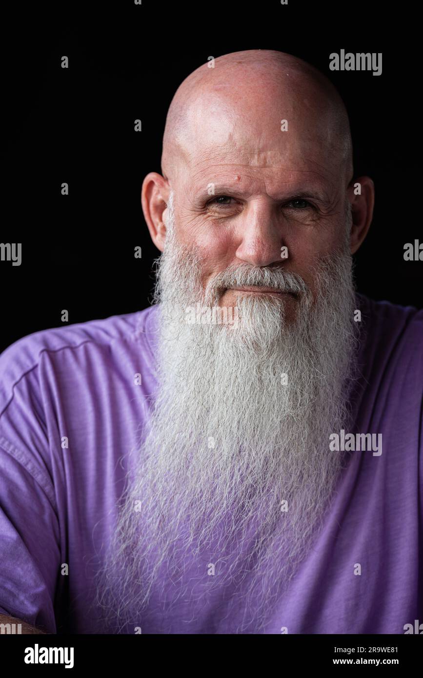 Ritratto di un uomo con barba grigia lunga che indossa una t-shirt viola e primo piano con la testa Foto Stock