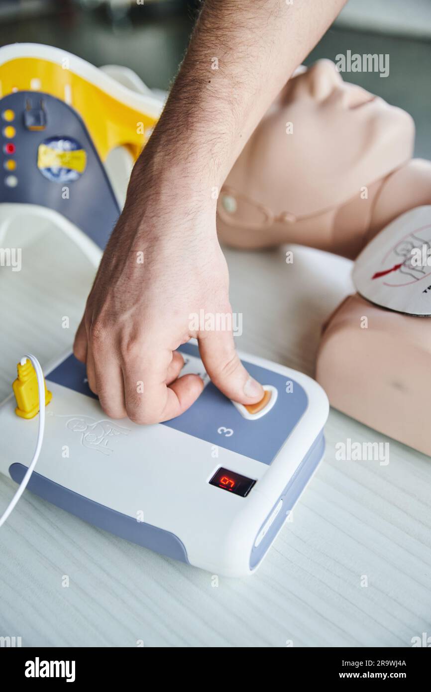 Vista parziale dell'operatore sanitario che utilizza il defibrillatore automatico durante la rianimazione cardiaca sul manichino RCP, apprendimento pratico del primo soccorso Foto Stock