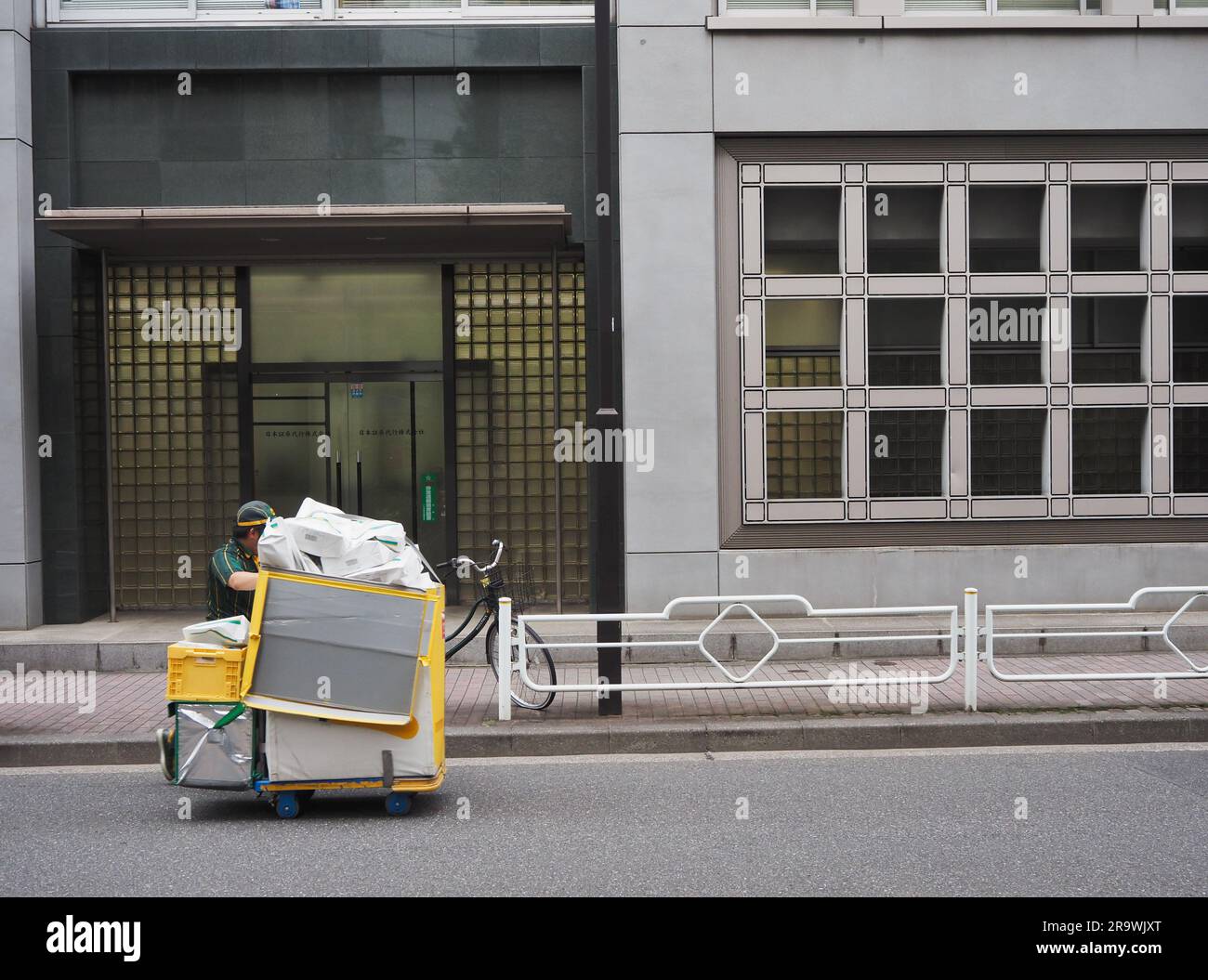 TOKYO, GIAPPONE - 27 giugno 2023: Un carrello della Yamato Transport Company (Kuroneko) viene spinto lungo una strada accanto a un edificio per uffici nell'area di Kayabacho a Tokyo Foto Stock