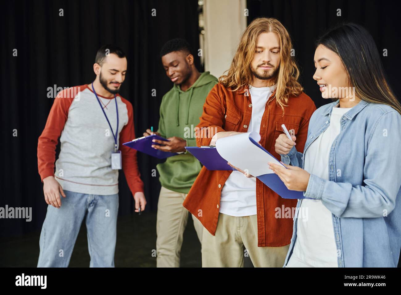 seminario medico e formazione di pronto soccorso, giovane donna asiatica con clipboard che parla con l'uomo a pelo lungo vicino istruttore e partecipante afro-americano, Foto Stock