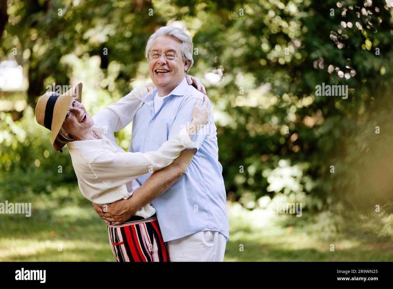 Germania, coppia anziana vestita per l'estate, abbracciata e divertita nella natura Foto Stock
