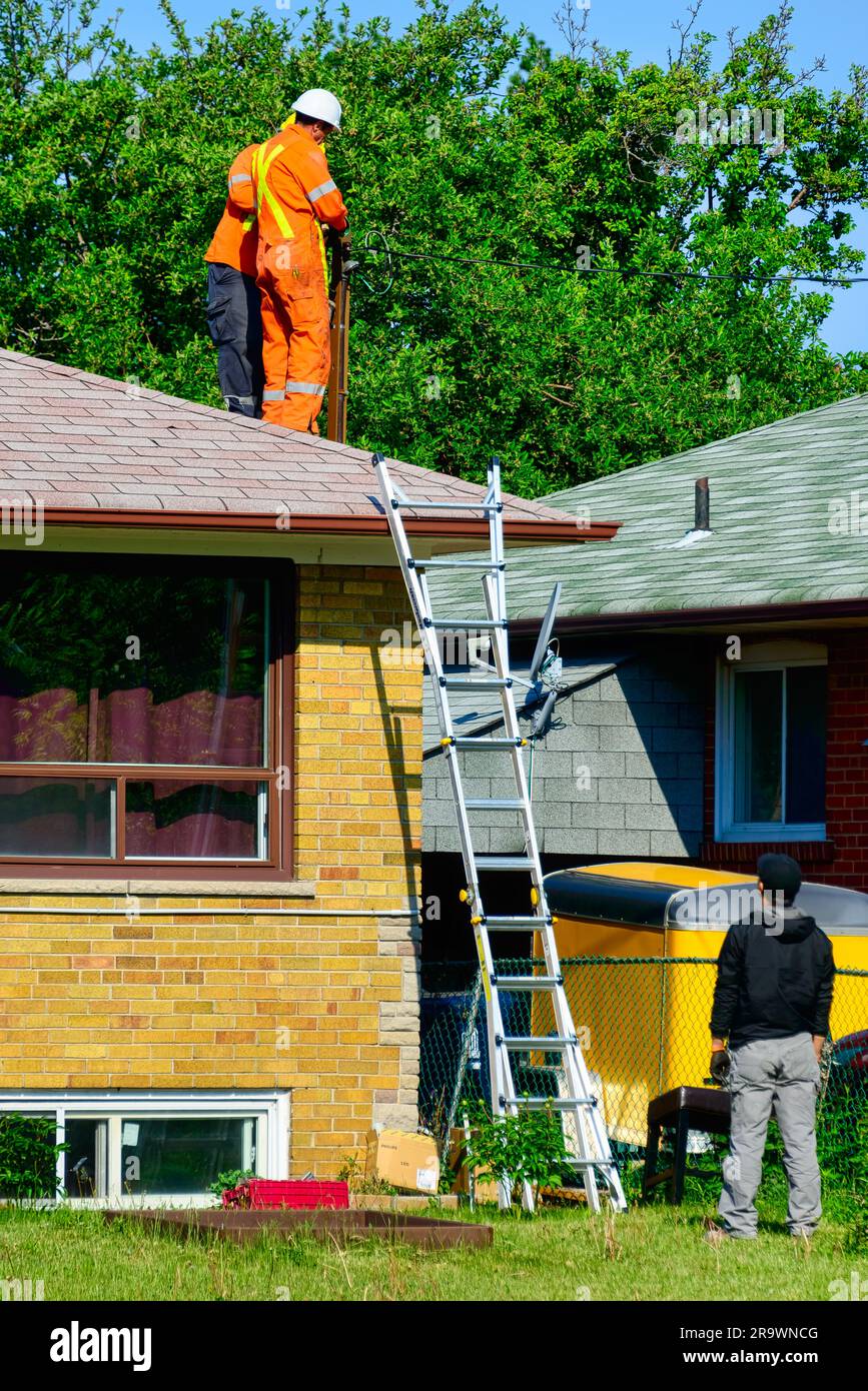 Appaltatore di elettricisti che lavora sul tetto di una casa Foto Stock