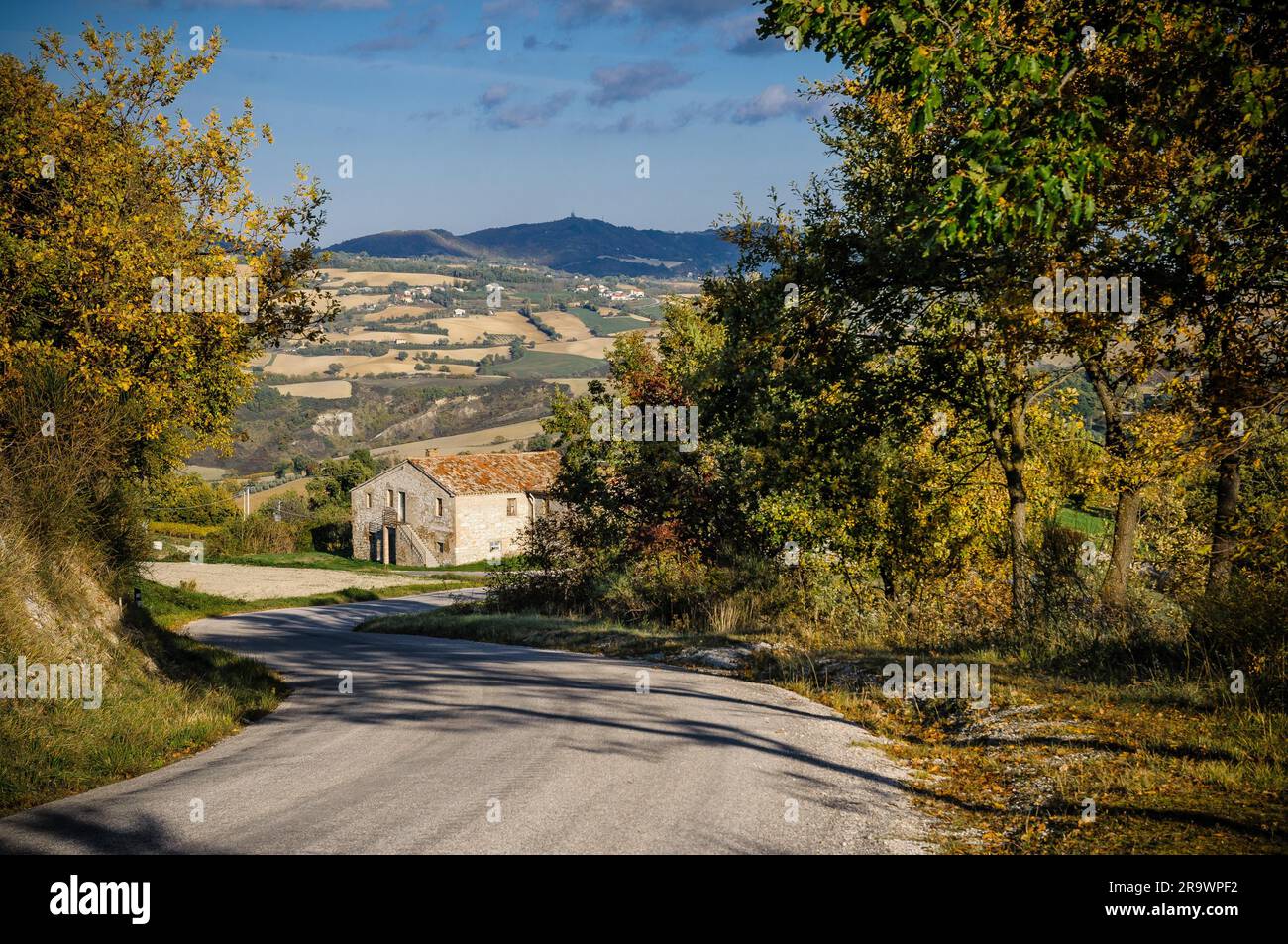 In discesa su una stradina nei pressi di Urbino in Italia. Una casa antica appare una curva Foto Stock