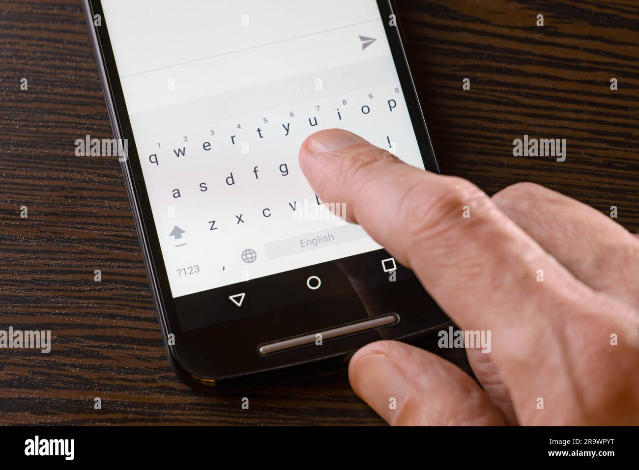 Un uomo è la digitazione di un sms sulla tastiera del suo nero smartphone Foto Stock