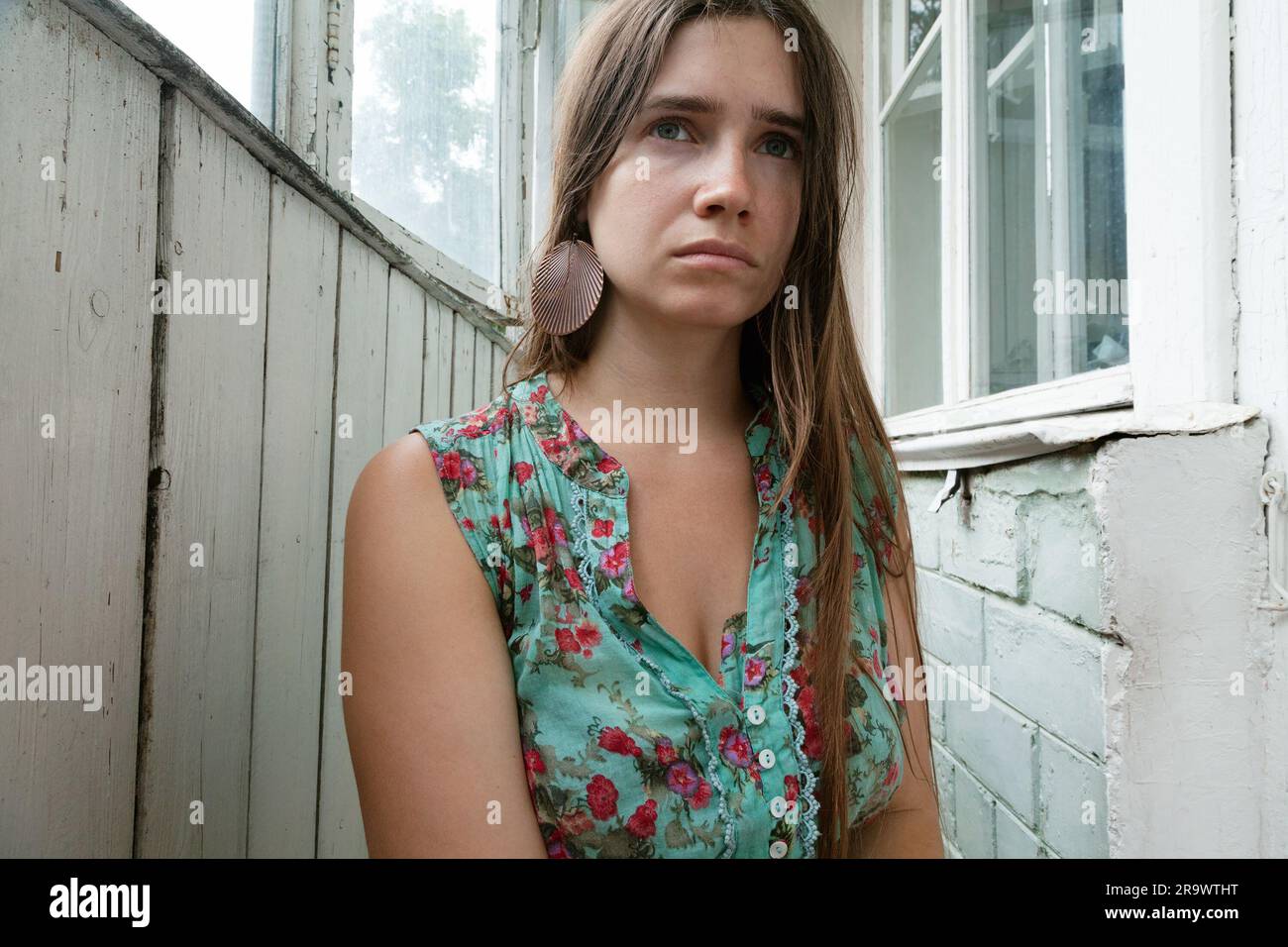 Bellezza naturale di una giovane donna vestita con un vestito vintage in un interno grungy. Triste donna caucasica malinconica che indossa abiti boho chic in un rusti Foto Stock