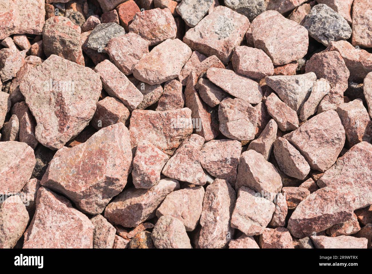 Macro di rosa pietre frantumate (roccia angolare) utilizzato per la costruzione di strade Foto Stock