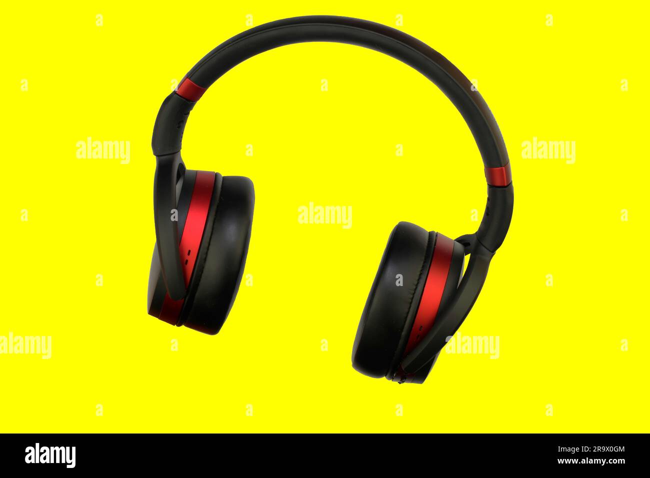 Cuffia stereo wireless. Cuffie cordless nere e rosse. Auricolari isolati su sfondo giallo con percorso di ritaglio. Immagine macro orizzontale, Chiudi- Foto Stock