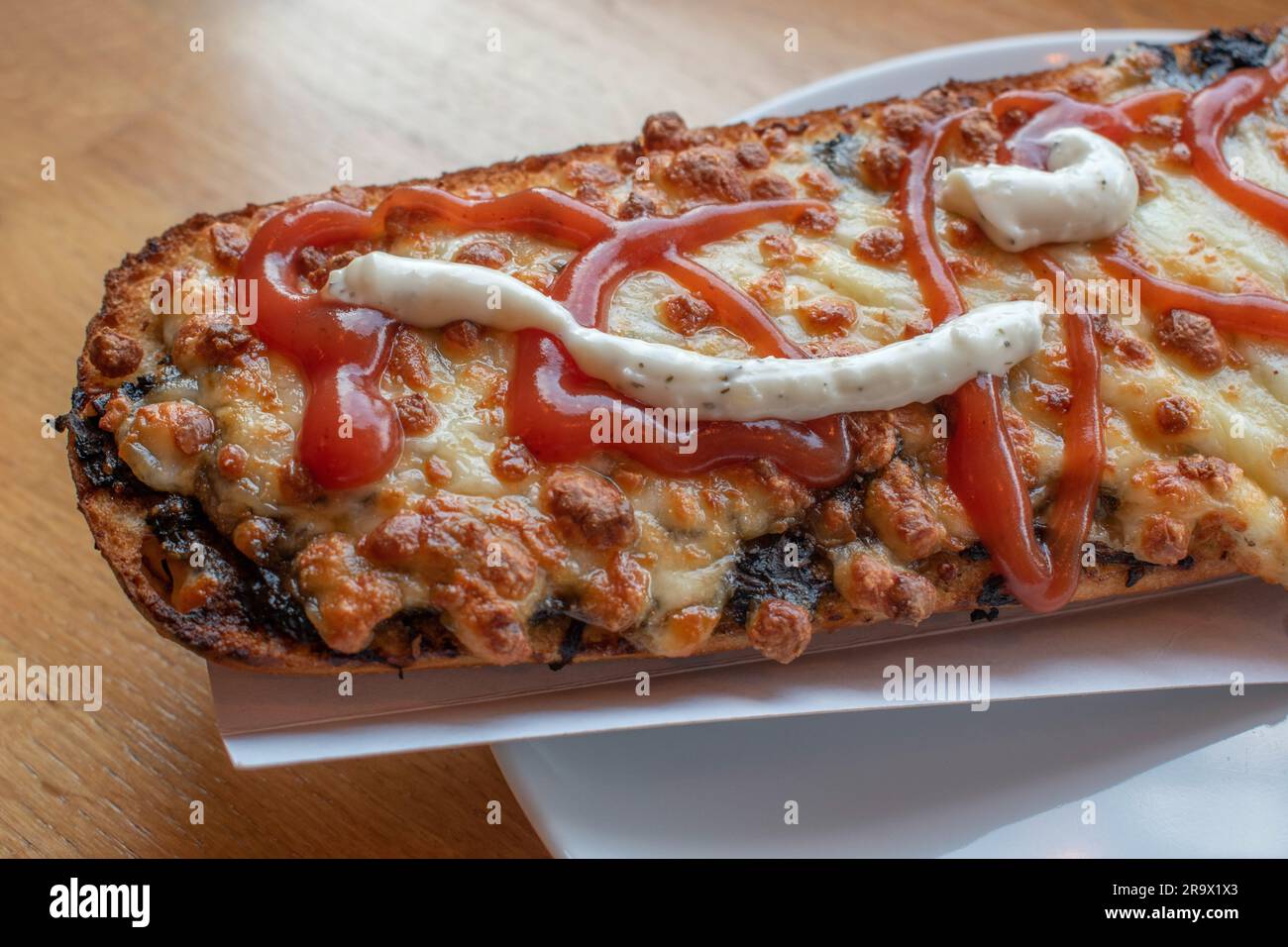 scopri il gusto della polonia con un appetitoso zapiekanka, un panino caldo su mezza baguette, abbondantemente riempito con vari condimenti, che offre una Foto Stock