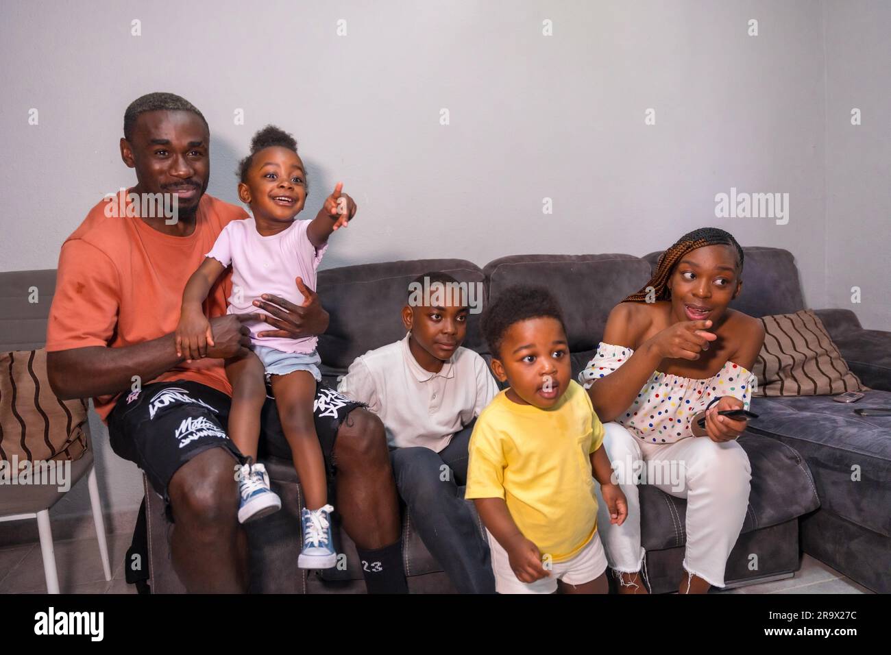 Ritratto di una famiglia di etnia africana nera con bambini sul divano a casa guardando la TV Foto Stock