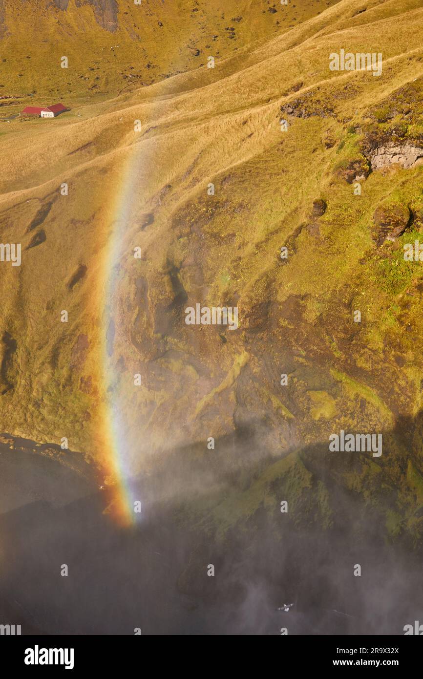 Un arco arcobaleno attraverso la collina, creato dallo spray della cascata di Skogafoss Falls, nel sud dell'Islanda. Foto Stock