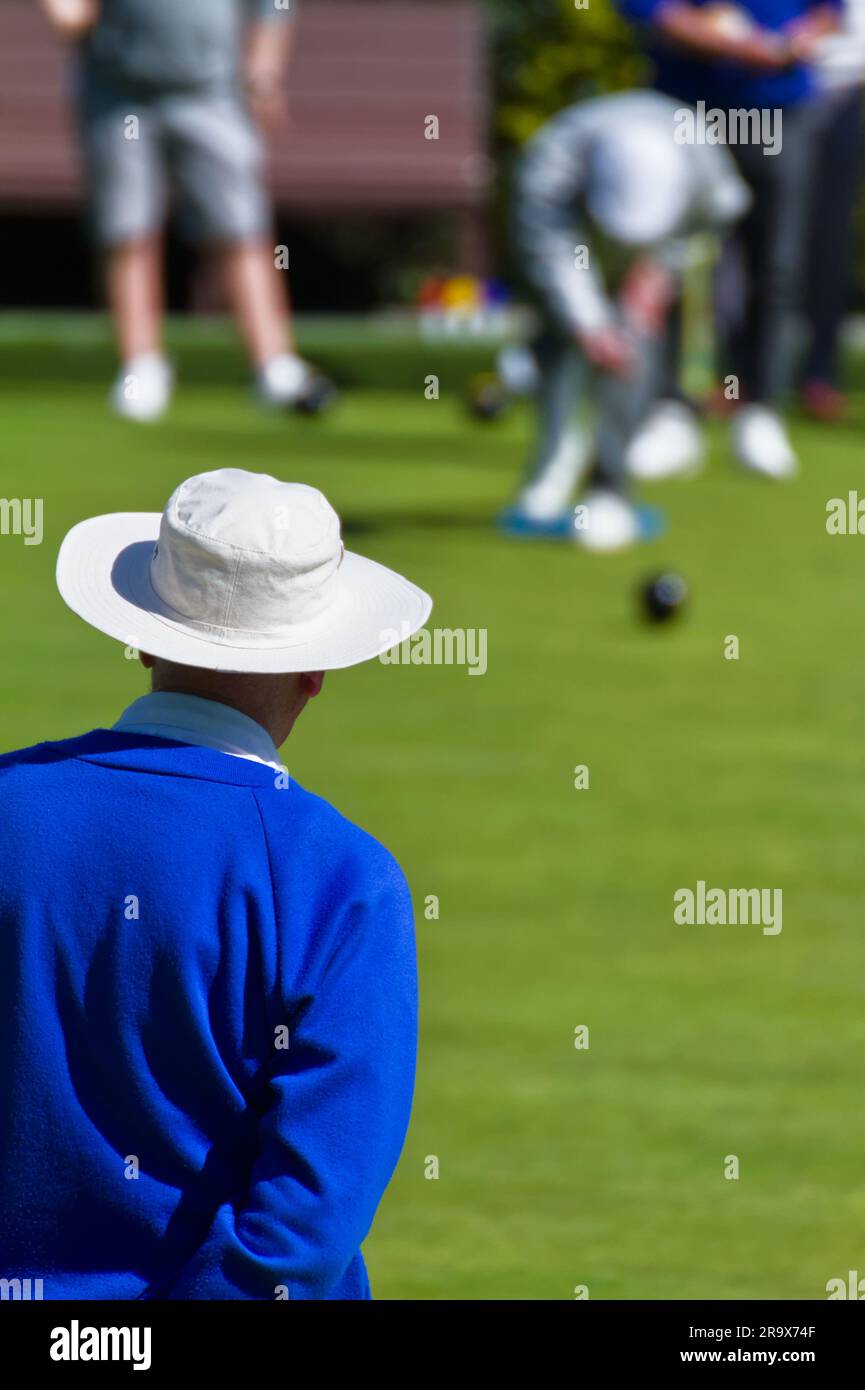 Giocatore di bocce con cappello bianco che guarda un altro giocatore lanciare Un Bowl, Inghilterra Regno Unito Foto Stock