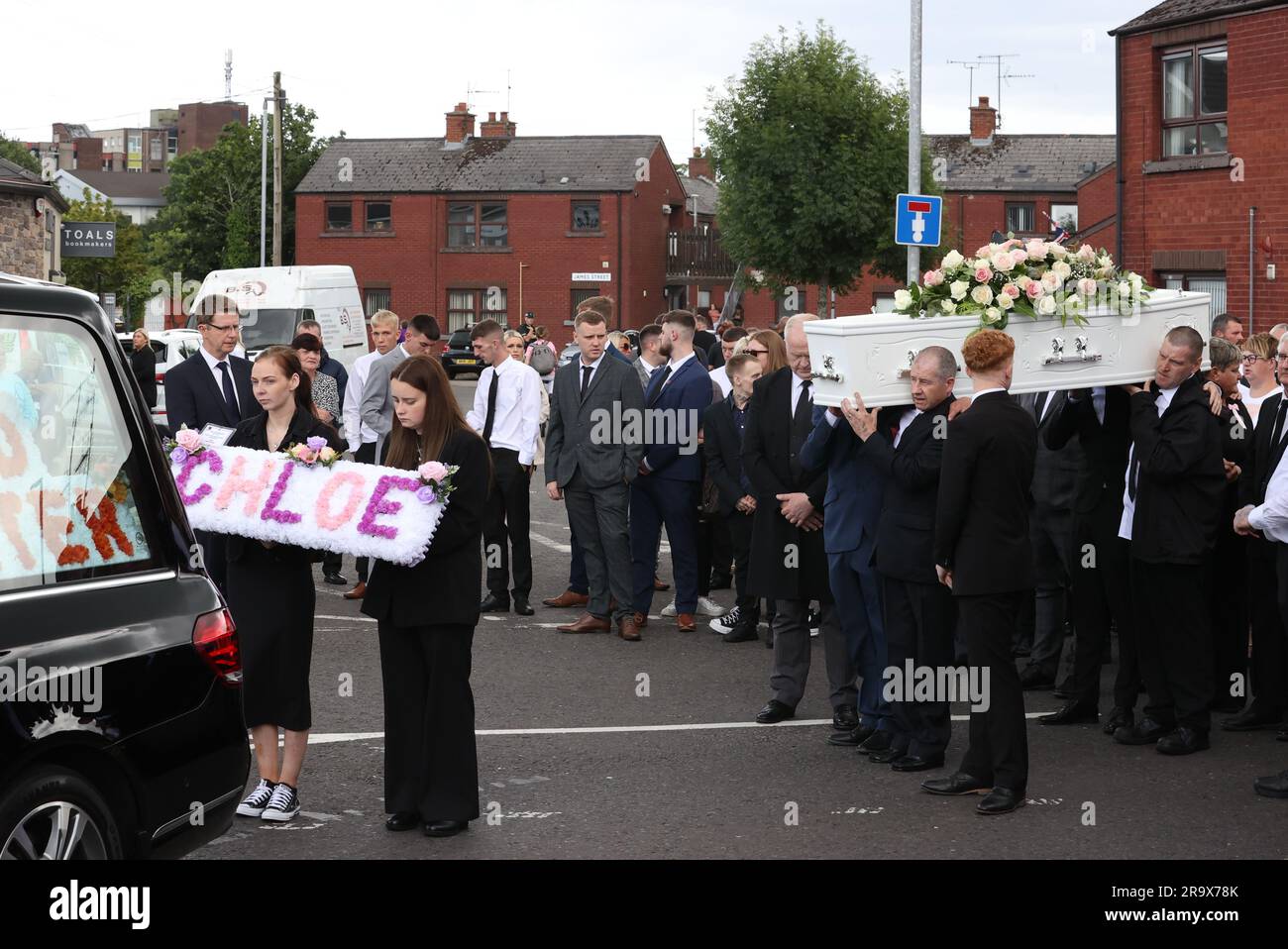 RITRASMETTENDO CORREGGENDO L'ORTOGRAFIA DELLE sorelle di KIRSTIE Chloe Mitchell, Kirstie (a sinistra) e Nadine portano una corona davanti alla sua bara mentre viene portata lungo Larne Street, a Ballymena. Data foto: Giovedì 29 giugno 2023. Foto Stock