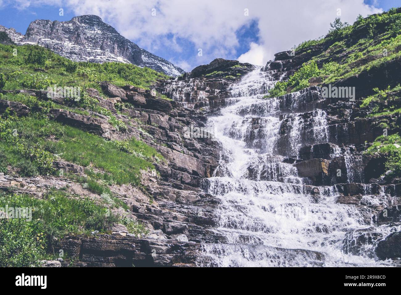 Cascata di montagna con scogliere ruvida e cielo blu Foto Stock