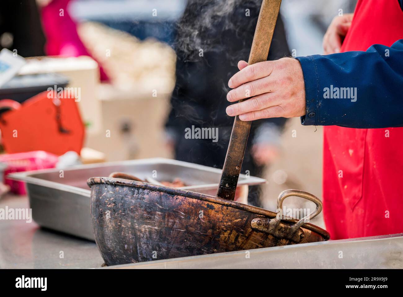 Cucina esterna con un uomo sotto agitazione in un hot pot con fumo intorno in estate Foto Stock