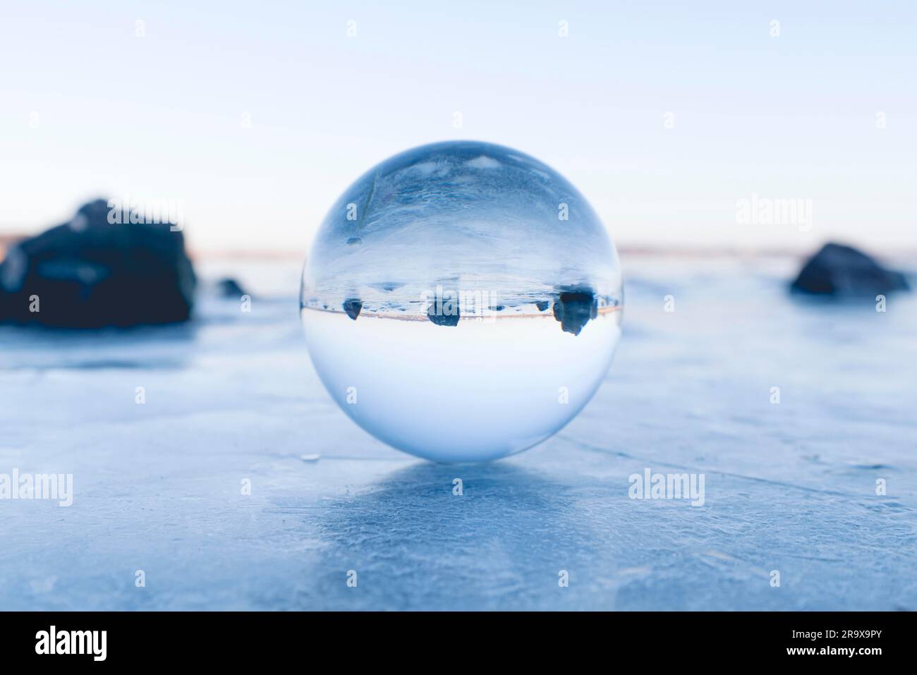 Sfera di vetro in equilibrio su ghiaccio su un lago ghiacciato al mattino sunrise Foto Stock