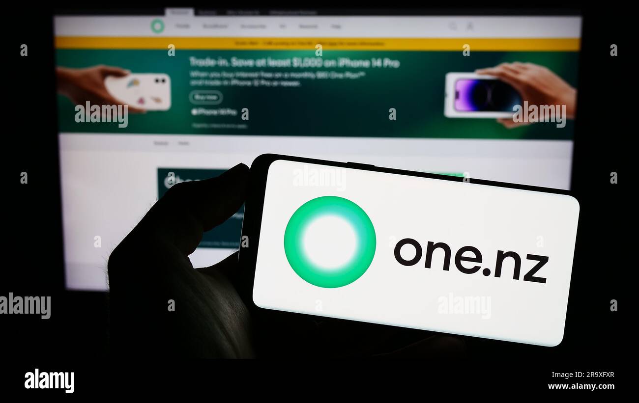Persona in possesso di un cellulare con il logo della società One New Zealand Group Limited (One NZ) sullo schermo davanti alla pagina Web. Concentrarsi sul display del telefono. Foto Stock
