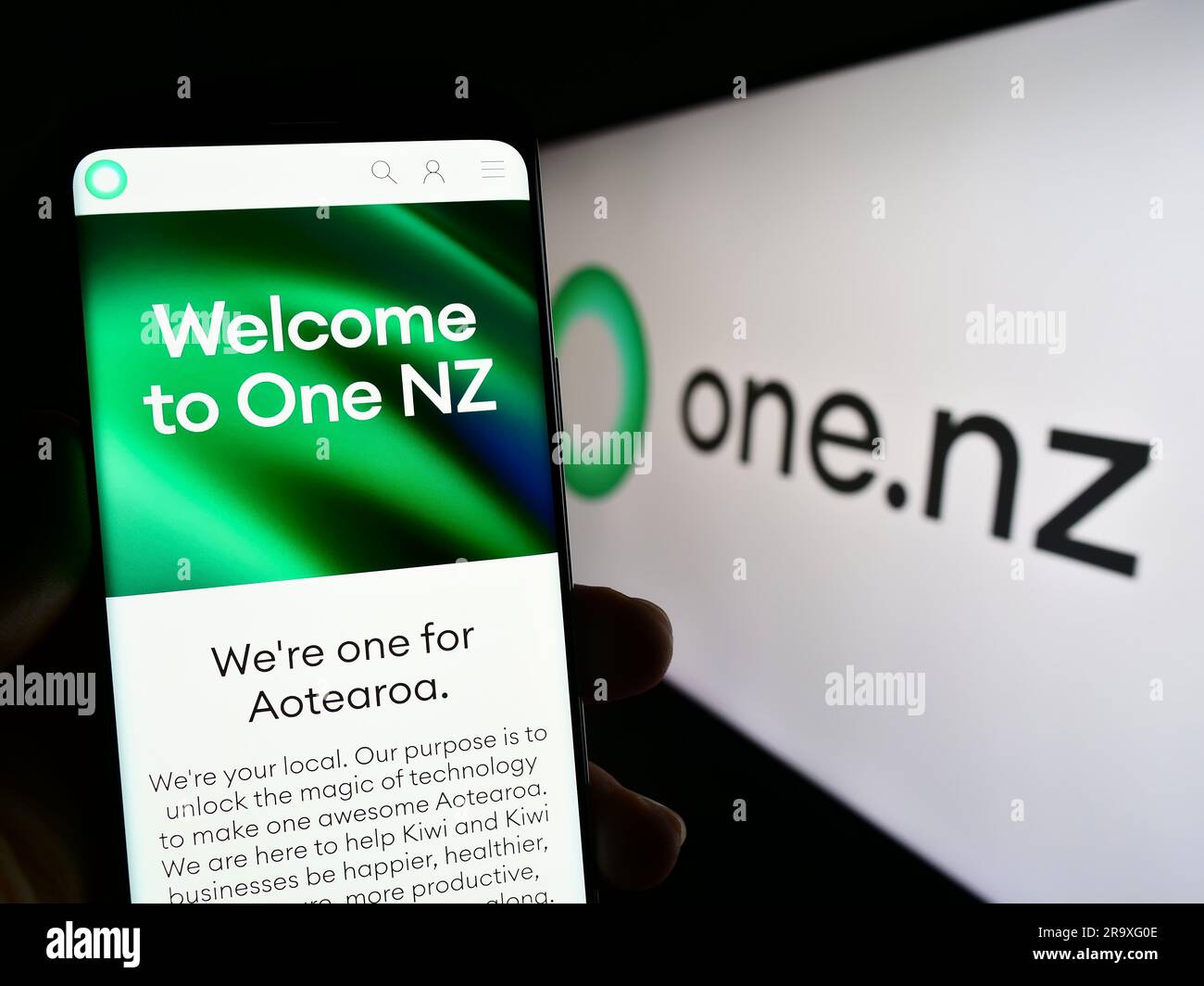 Persona in possesso di cellulare con pagina Web dell'azienda One New Zealand Group Limited (One NZ) sullo schermo con logo. Concentrarsi sul centro del display del telefono. Foto Stock