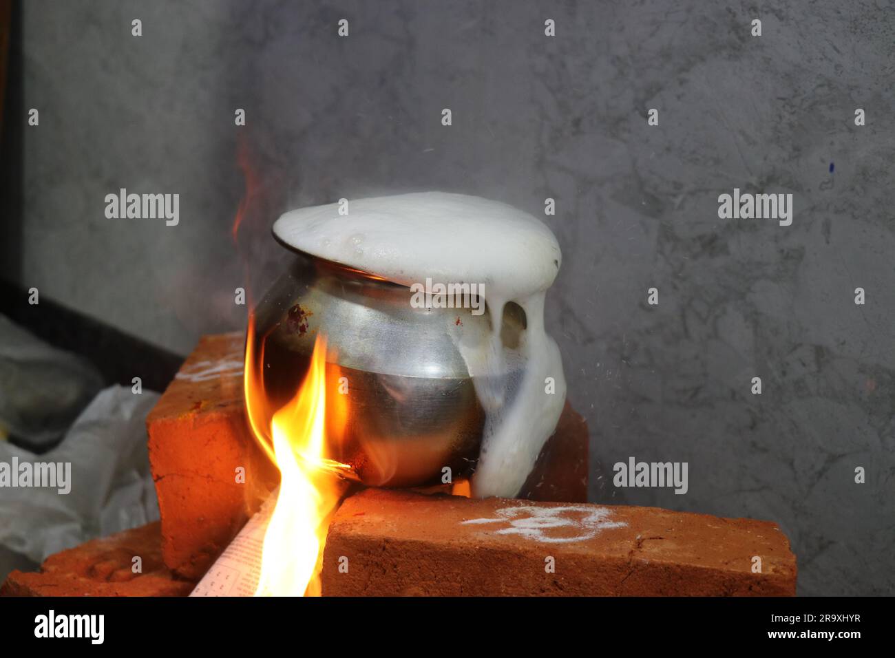 Il latte è traboccante su una stufa a mattoni a causa dell'eccessiva bollitura come tradizione in India per la cerimonia di riscaldamento della casa Foto Stock