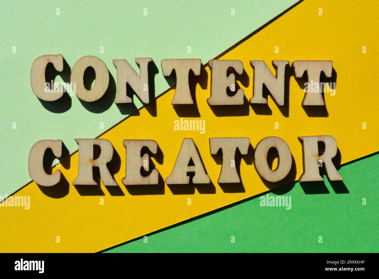 Content Creator, parole in lettere alfabetiche di legno isolate su sfondo giallo e verde come intestazione del banner Foto Stock