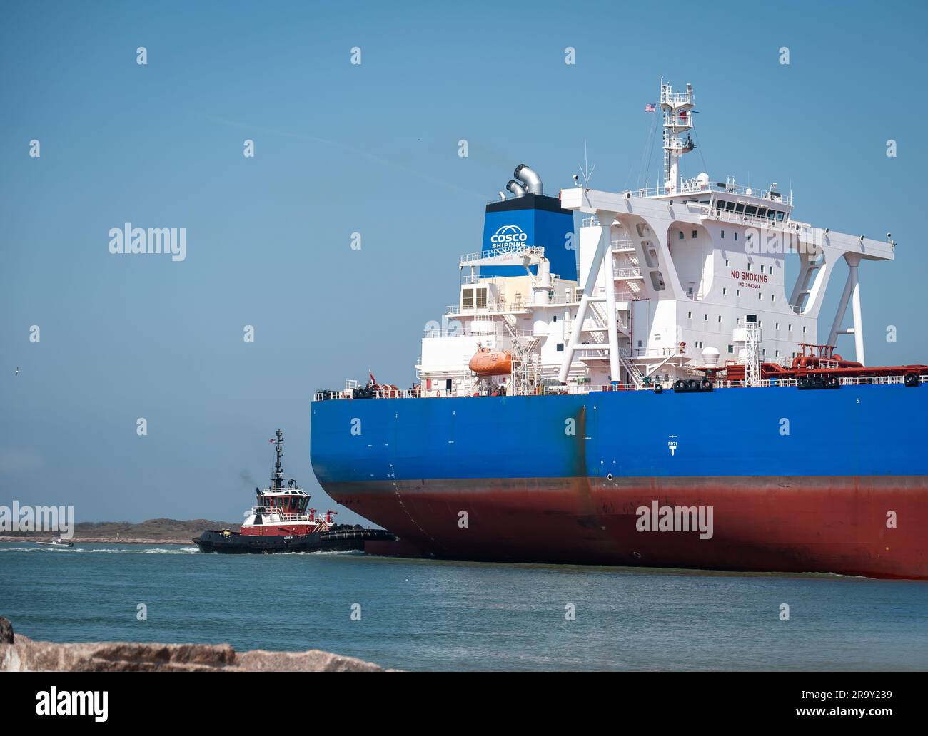PORT ARANSAS, TX - 26 FEB 2023: Stern di YUAN fu YANG, una nave petroliera grezza, e rimorchiatore, che naviga oltre il South Jetty sul canale di navigazione. Foto Stock