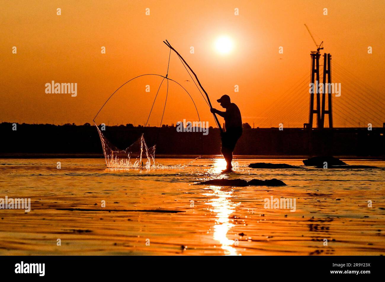 Non esclusiva: ZAPORIZHZHIA, UCRAINA - 28 GIUGNO 2023 - Un uomo pesca sul fiume Dnipro che è diventato poco profondo dopo che i russi hanno fatto saltare in aria il Kakhovk Foto Stock