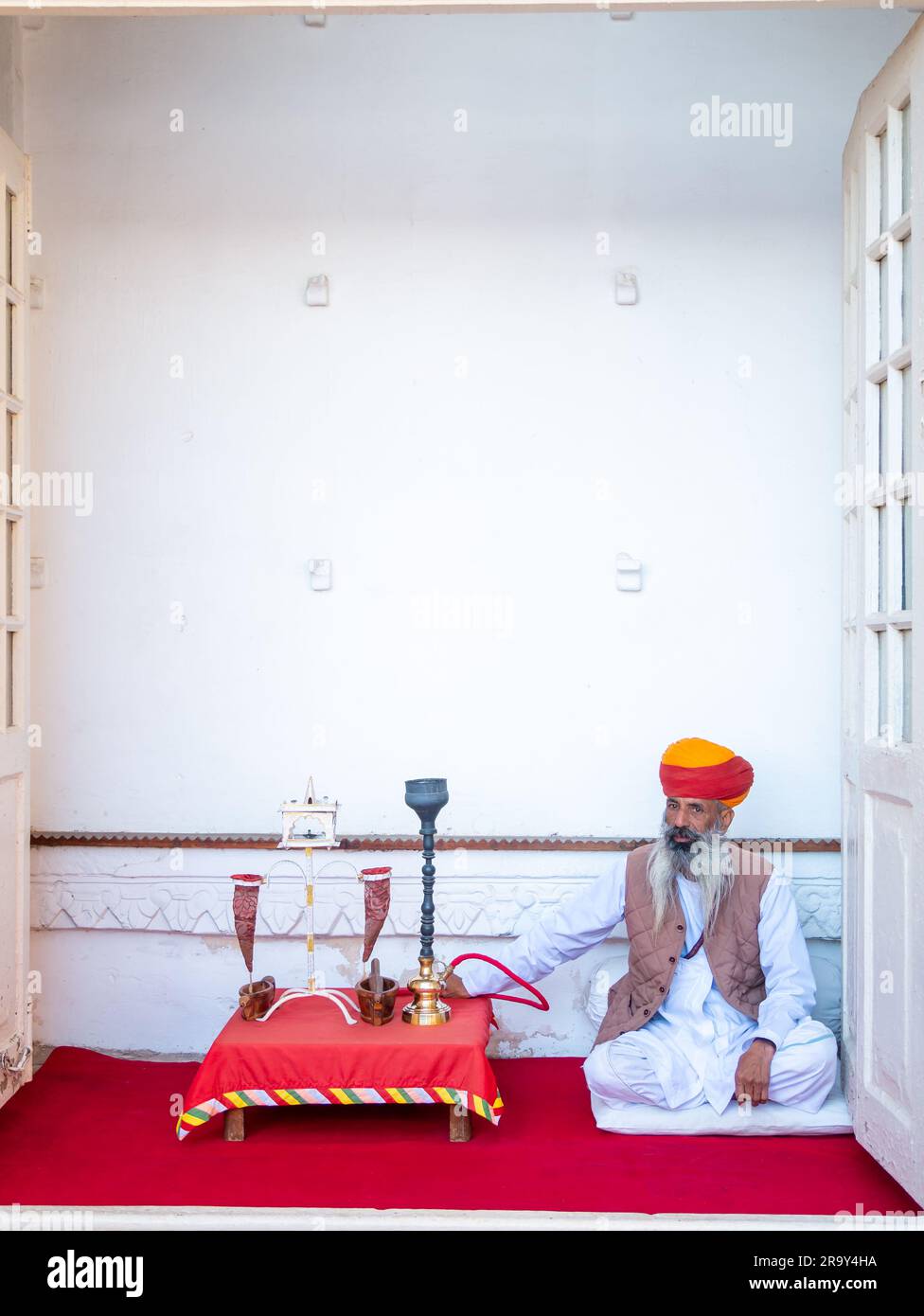 Udaipur, India - 29 dicembre 2022: Uomo Rajasthani vecchio e non identificato, in abbigliamento tradizionale, che fuma con metodi tradizionali Foto Stock
