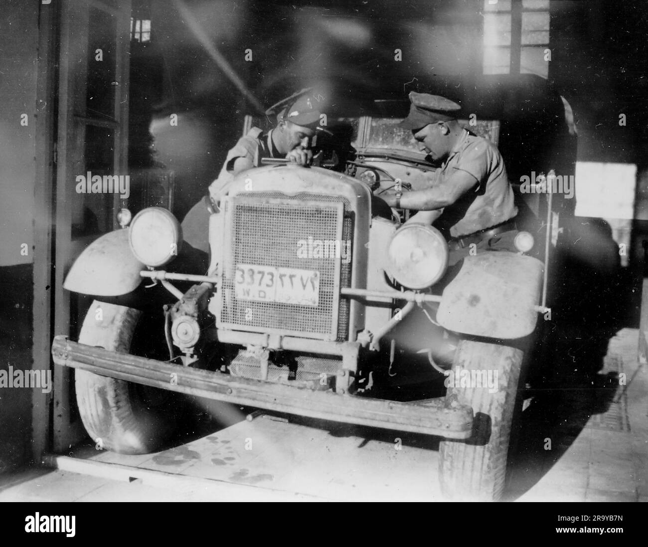 Un veicolo militare britannico in un capannone meccanico in Palestina, trascurato da due meccanici militari. Palestina, c1930. Si tratta di una fotografia tratta da un album di scatti, durante l'occupazione della Palestina da parte dell'esercito britannico, con foto provenienti dalla Palestina e dal Regno Unito, tra cui devil's Jump vicino a Churt nel Surrey e devil's Punch Bowl. L'addestramento sembra essere a Hursley Camp, vicino a Winchester. La Gran Bretagna amministrò la Palestina per conto della società delle Nazioni tra il 1920 e il 1948, un periodo denominato "mandato britannico”. Foto Stock