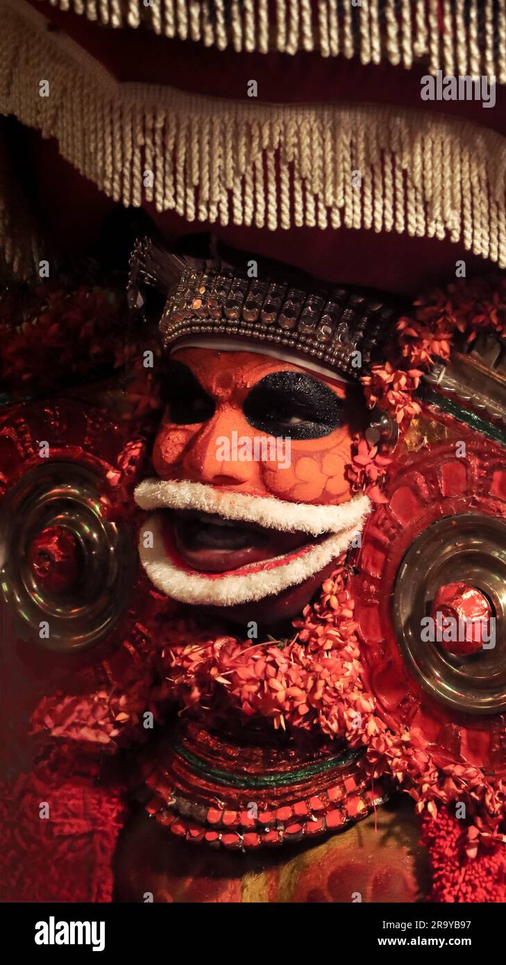 primo piano di teyam dai colori luminosi e decorati, una forma d'arte tradizionale del kerala, simbolo di culto nell'induismo eseguito da un artista Foto Stock