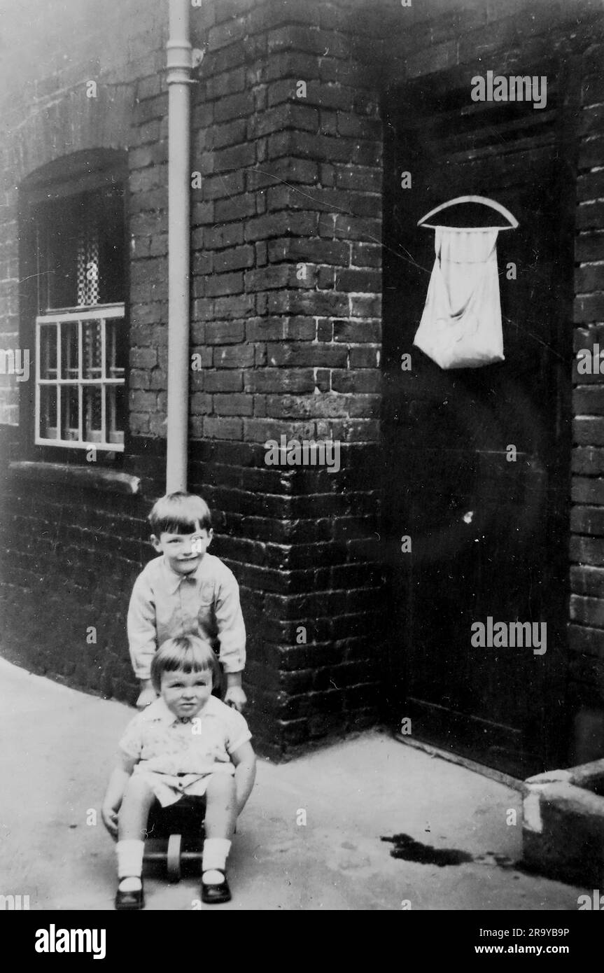 Un ragazzo e una ragazza che giocano fuori da una casa. Surrey, c1930. Si tratta di una fotografia tratta da un album di scatti, durante l'occupazione della Palestina da parte dell'esercito britannico, con foto provenienti dalla Palestina e dal Regno Unito, tra cui devil's Jump vicino a Churt nel Surrey e devil's Punch Bowl. L'addestramento sembra essere a Hursley Camp, vicino a Winchester. La Gran Bretagna amministrò la Palestina per conto della società delle Nazioni tra il 1920 e il 1948, un periodo denominato "mandato britannico”. Foto Stock
