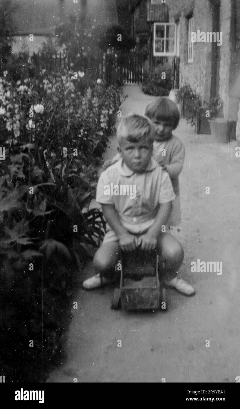 Una ragazza che spinge un ragazzo su un carrello. Surrey, c1930. Si tratta di una fotografia tratta da un album di scatti, durante l'occupazione della Palestina da parte dell'esercito britannico, con foto provenienti dalla Palestina e dal Regno Unito, tra cui devil's Jump vicino a Churt nel Surrey e devil's Punch Bowl. L'addestramento sembra essere a Hursley Camp, vicino a Winchester. La Gran Bretagna amministrò la Palestina per conto della società delle Nazioni tra il 1920 e il 1948, un periodo denominato "mandato britannico”. Foto Stock