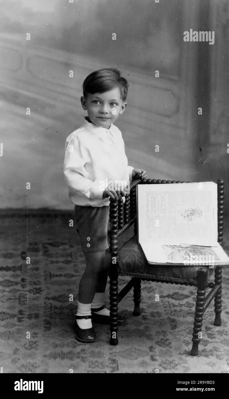 Una foto in posa di un ragazzo in piedi accanto a una sedia angolare con un libro aperto su di essa, c1930. Si tratta di una fotografia tratta da un album di scatti, durante l'occupazione della Palestina da parte dell'esercito britannico, con foto provenienti dalla Palestina e dal Regno Unito, tra cui devil's Jump vicino a Churt nel Surrey e devil's Punch Bowl. L'addestramento sembra essere a Hursley Camp, vicino a Winchester. La Gran Bretagna amministrò la Palestina per conto della società delle Nazioni tra il 1920 e il 1948, un periodo denominato "mandato britannico”. Foto Stock