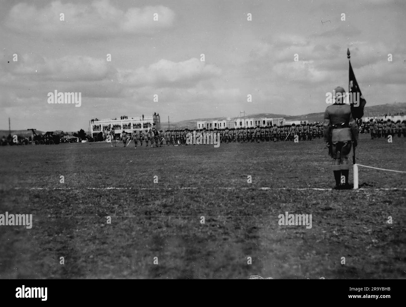 Campo da parata con un portabandiera in primo piano. Questa fotografia è tratta da un album fotografico di fotografie, c1937, durante l'occupazione della Palestina da parte dell'esercito britannico. La Gran Bretagna amministrò la Palestina per conto della società delle Nazioni tra il 1920 e il 1948, un periodo denominato "mandato britannico”. Foto Stock