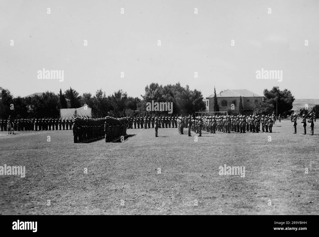 Campo da parata con edifici di baracche sullo sfondo e soldati in parata. Questa fotografia è tratta da un album fotografico di fotografie, c1937, durante l'occupazione della Palestina da parte dell'esercito britannico. La Gran Bretagna amministrò la Palestina per conto della società delle Nazioni tra il 1920 e il 1948, un periodo denominato "mandato britannico”. Foto Stock