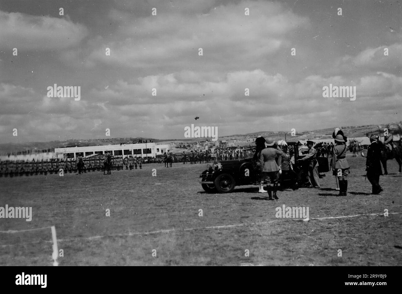 Scena da un terreno di parata con un veicolo civile, forse un dignitario, in primo piano. Questa fotografia è tratta da un album fotografico di fotografie, c1937, durante l'occupazione della Palestina da parte dell'esercito britannico. La Gran Bretagna amministrò la Palestina per conto della società delle Nazioni tra il 1920 e il 1948, un periodo denominato "mandato britannico”. Foto Stock