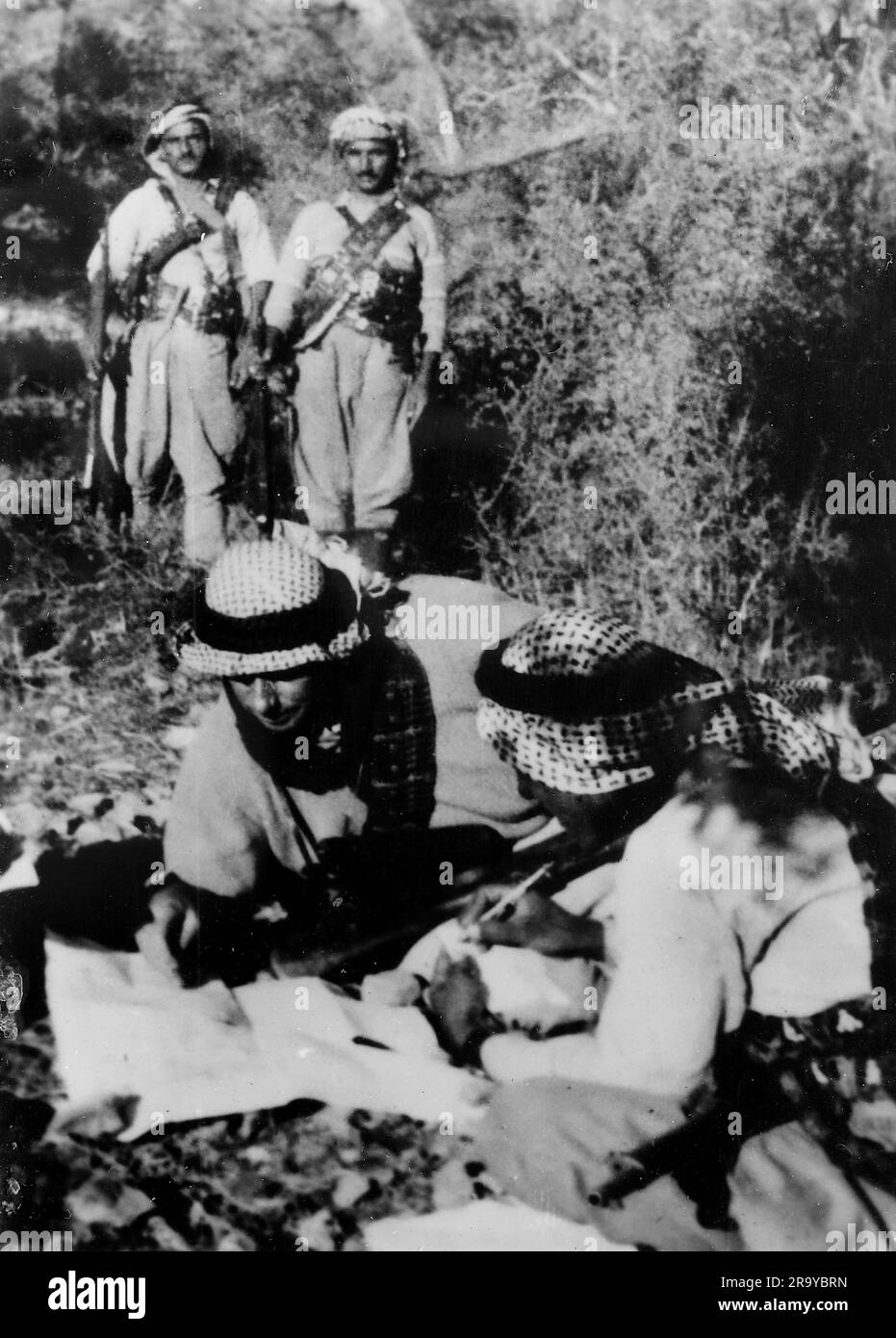 Un gruppo di arabi, tra cui due che studiano una mappa, parte di un gruppo descritto come "briganti" (un membro di una banda che imboscava e derubava le persone nelle foreste e nelle montagne). Questa fotografia è tratta da un album fotografico di fotografie, c1937, durante l'occupazione della Palestina da parte dell'esercito britannico. La Gran Bretagna amministrò la Palestina per conto della società delle Nazioni tra il 1920 e il 1948, un periodo denominato "mandato britannico”. Foto Stock